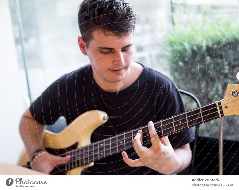 Junger Mann spielt Bassgitarre spielen Gitarre Musik stimmen Fähigkeit ausführen Musiker Instrument Klang Melodie Gesang Hobby jung männlich lernen Lifestyle