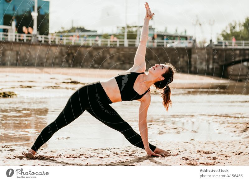 Flexible Frau beim Yoga in Dreieckspose Triangel-Pose Strand trikonasana üben beweglich Sommer Asana schlank Sportbekleidung passen sich[Akk] entspannen