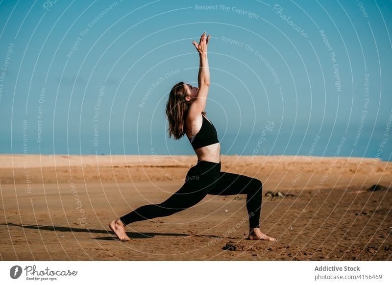 Flexible Frau beim Yoga in der Crescent-Variante Strand Pose üben beweglich virabhadrasana Sommer schlank Sportbekleidung passen sich[Akk] entspannen
