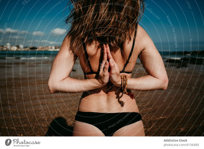 Schlanke Frau beim Yoga am Meeresstrand Namaste gestikulieren Hand hinter dem Rücken üben Asana Pose Meeresufer beweglich sonnig Seeküste Natur Gleichgewicht