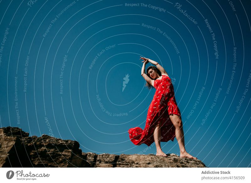 Anmutige Frau im Kleid auf felsigem Hügel rot Angebot Freude sich[Akk] bewegen schlank Barfuß Felsen Blauer Himmel wolkenlos Himmel (Jenseits) Natur