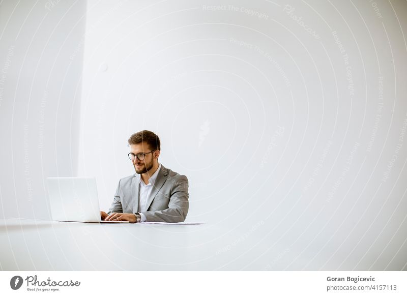 Junger Mann arbeitet am Laptop in hellem Büro Erwachsener attraktiv schön hinten Business Kaukasier Mitteilung Computer selbstbewusst Tag Schreibtisch elegant