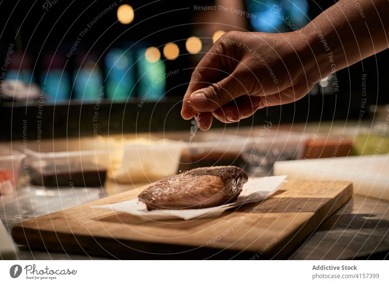 Appetitliches Stück Rindfleisch auf einem Holzbrett in der Küche Scheibe Restaurant Gewürz Koch hinzufügen bestäuben Fleisch Küchenchef Lebensmittel Salz