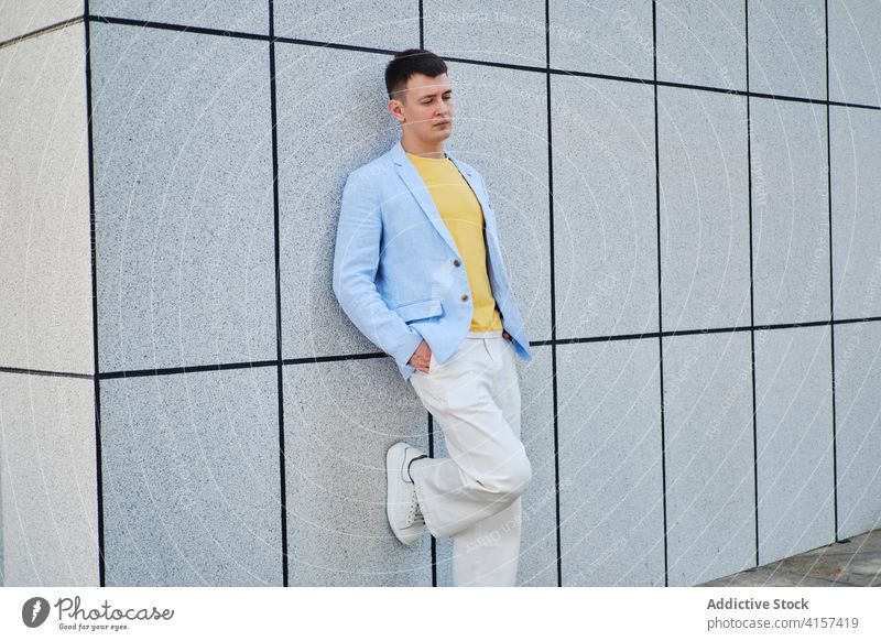 Junger Mann auf der Straße, der sich an die Wand lehnt und nach unten schaut Erwachsener Porträt Hintergrund blau gelb männlich einsam sehr wenige Stimmung Sinn