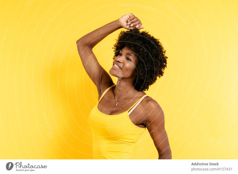 Glückliche schwarze Frau mit lockigem Haar Lächeln Stil Arm angehoben krause Haare positiv modern Farbe hell Afro-Look Afroamerikaner ethnisch Freude froh