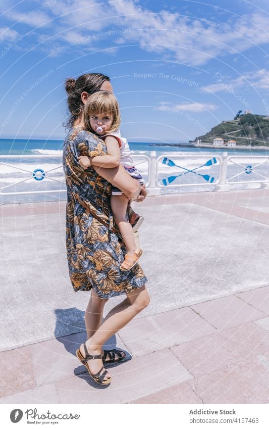 Frau mit kleinem Mädchen auf Böschung im Sommer Mutter Tochter MEER Urlaub Strandpromenade Stauanlage Spazierweg sonnig Zusammensein niedlich wenig Glück Kind