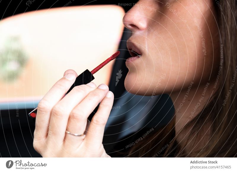Crop-Frau trägt Lippenstift im Auto auf Make-up PKW bewerben Vorschein Schönheit Routine Gesicht Innenbereich modern Automobil trendy Stil elegant Fokus Mode