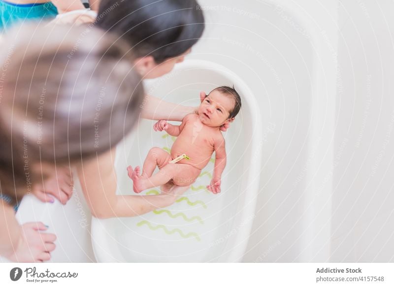 Anonymes Elternteil und Kind waschen Säugling im Waschbecken Waschen Baby Becken Wasser weinen heimwärts Pflege Angebot Liebe neugeboren Sauberkeit Bad