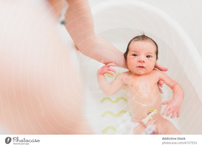 Anonymes Elternteil wäscht Kleinkind im Waschbecken Waschen Baby Becken Wasser weinen heimwärts Pflege Angebot Liebe Kind Säugling neugeboren Sauberkeit Bad