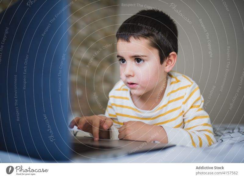 Kleines Kind verwendet Laptop zu Hause benutzend heimwärts wenig Apparatur Junge Browsen Schlafzimmer Surfen Internet Süchtige Gerät online Lifestyle männlich