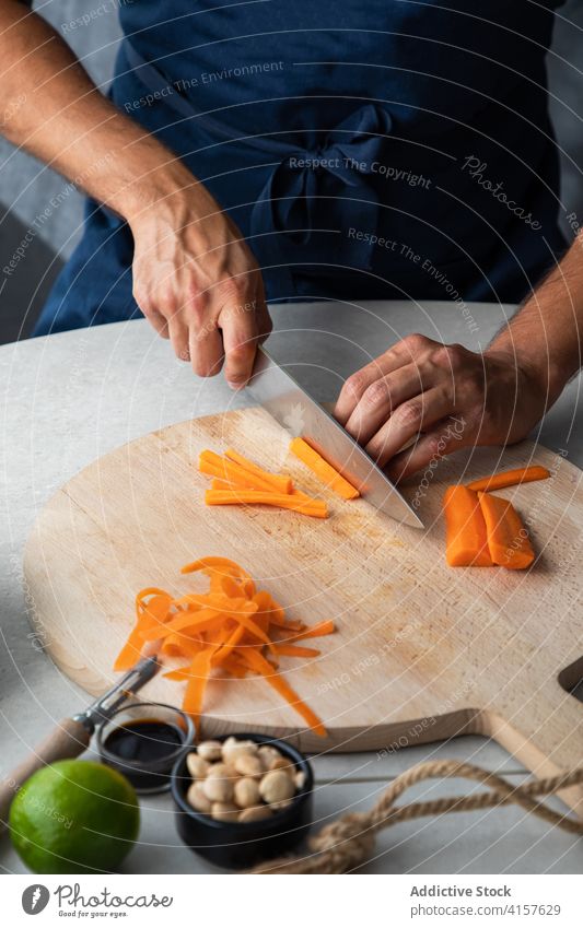 Koch schneidet Karotte auf Holzbrett Möhre geschnitten hacken Gemüse Lebensmittel vorbereiten frisch Küche kulinarisch Bestandteil Gesundheit Messer Mahlzeit