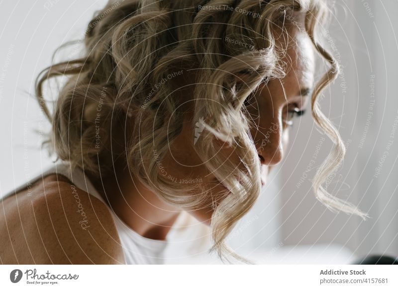 Unerkennbare Frau, die sich zu Hause die Haare lockt Locken Behaarung heimwärts bügeln Frisur krause Haare heimisch Leckerbissen elektronisch