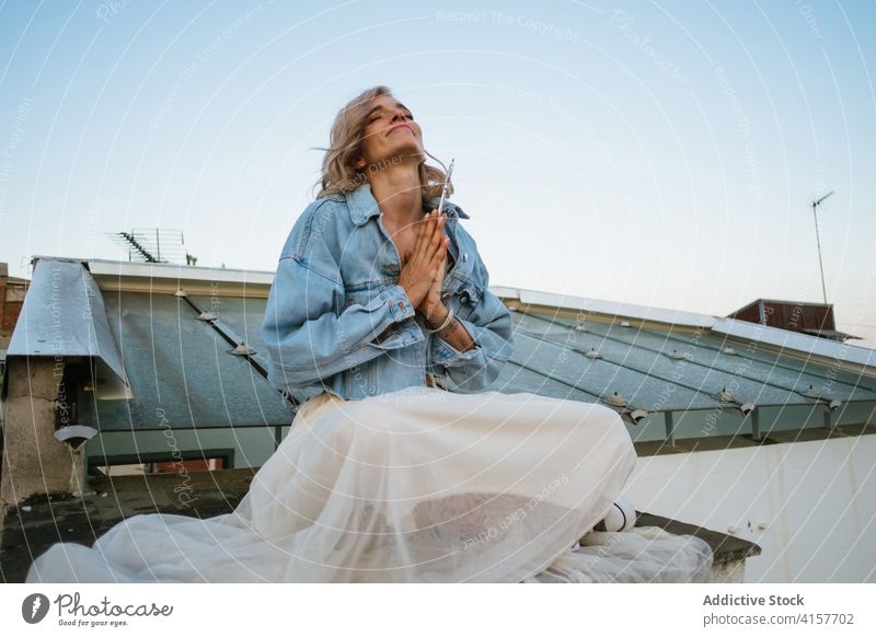 Sorglose Frau meditiert auf dem Dach meditieren Yoga Lotus-Pose Namaste Lächeln lässig Dachterrasse sorgenfrei Asana padmasana Windstille üben friedlich