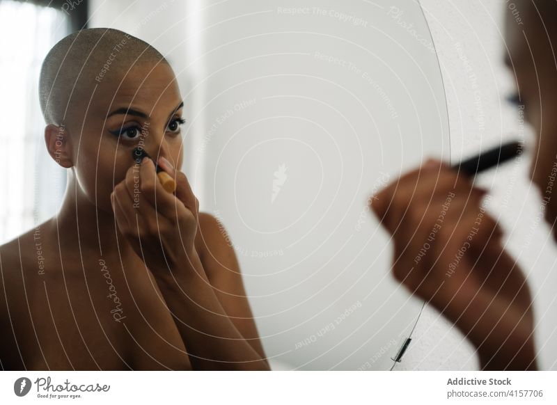Seriöse schwarze Frau beim Schminken zu Hause Make-up Gesicht bewerben heimwärts Applikator Bürste Spiegel Reflexion & Spiegelung ethnisch Afroamerikaner kahl