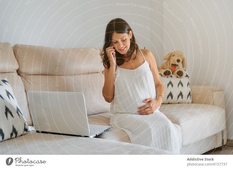 Schwangere Frau, die ihren Bauch berührt, während sie telefoniert Verantwortung Magen Mutterschaft reden Geburt Bonden neugeboren planen symbolisch berühren
