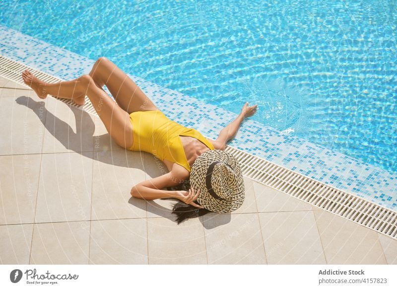 Schlanke Frau mit Hut beim Sonnenbaden am Pool Beckenrand Sommer Lügen Kälte genießen Resort sich[Akk] entspannen ruhen schlank Freizeit Tourist Bräune Wellness