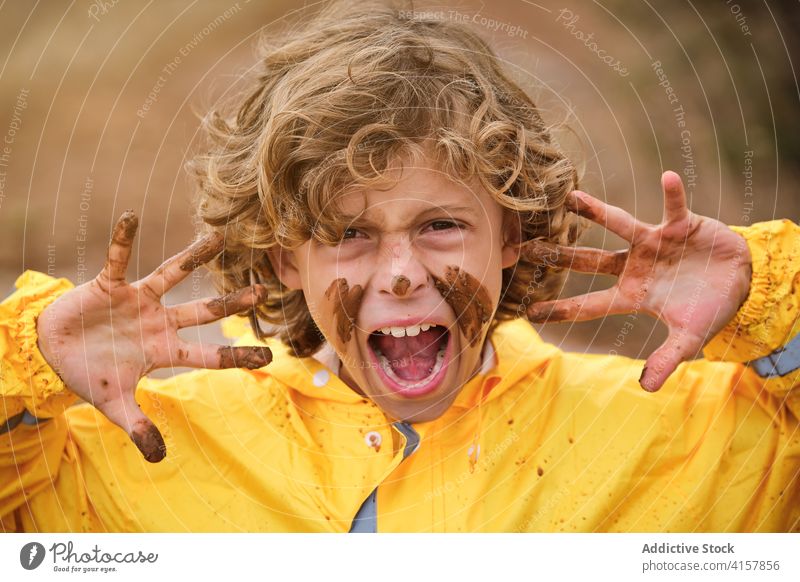 Porträt eines Jungen mit schlammigem Gesicht, der seine schmutzigen Hände mit einem wütenden Ausdruck zeigt Witz Säugling unordentlich spielerisch Finger Mark