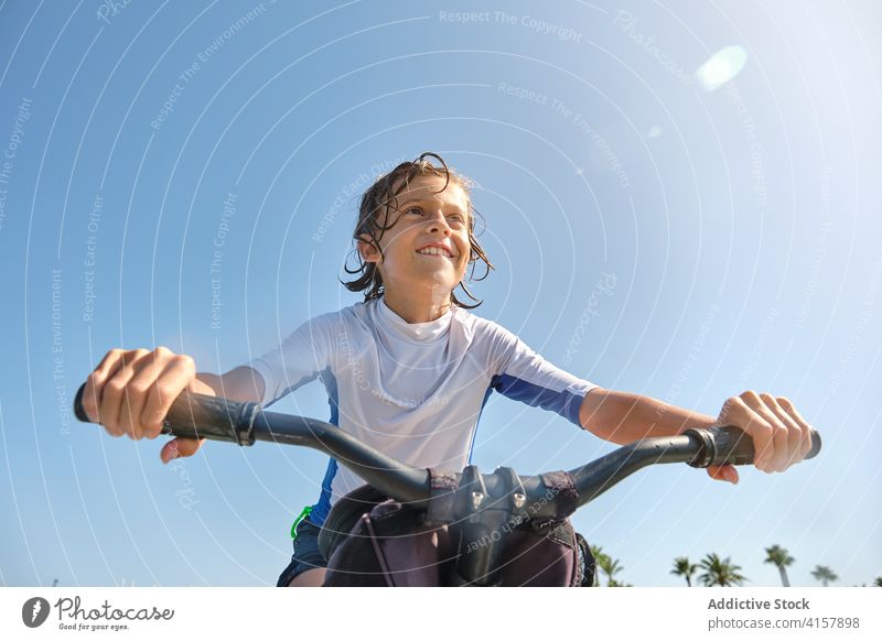 Vertikales Foto Junge strampelt auf einem Wasserfahrrad Befriedigung Lebensstile Sonnenstrahlen Ruhe Mitfahrgelegenheit Wellness gestikulieren Herausforderung