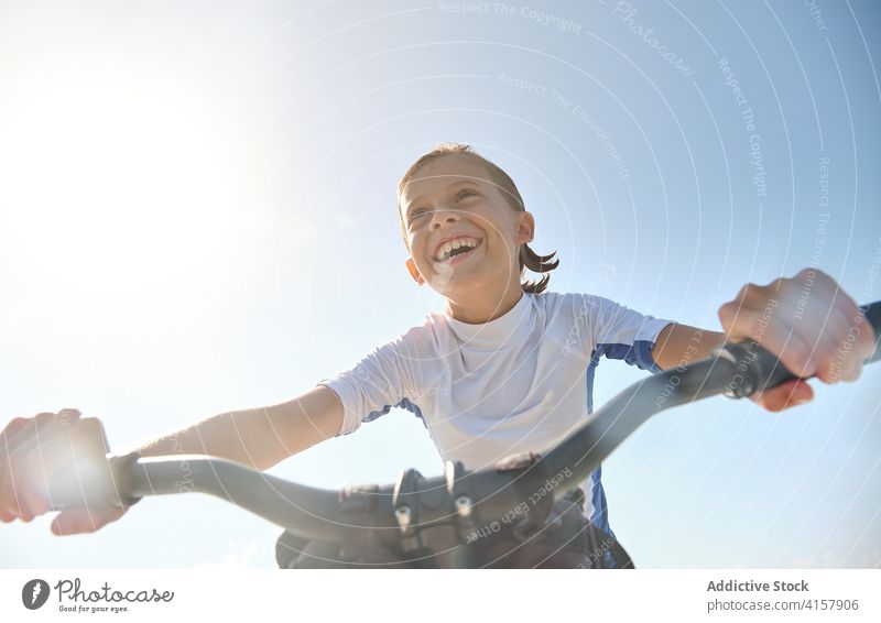 Vertikales Foto Kind lächelnd und strampelnd auf einem Wasserfahrrad Lächeln Sonnenstrahlen Wellness Herausforderung Ruhe Lebensstile Mitfahrgelegenheit