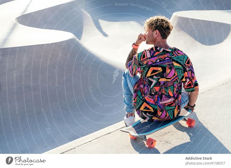 Hipster sitzt auf Skateboard in Skatepark Skater Mann trendy Stil Rampe Aktivität ruhen jung männlich Schlittschuh Lifestyle modern tausendjährig flippig Beton
