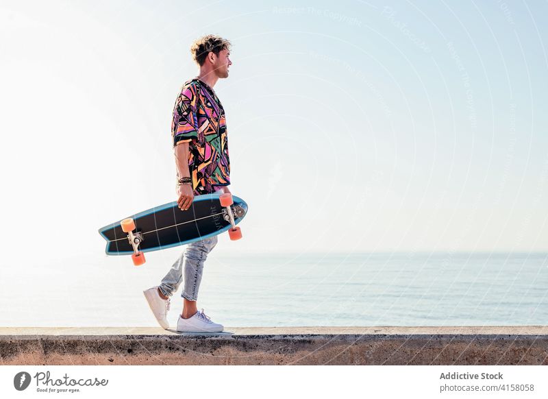 Stilvoller Mann mit Skateboard auf der Strandpromenade Skater MEER Stauanlage Hipster trendy Aktivität Sommer jung männlich Schlittschuh Lifestyle modern