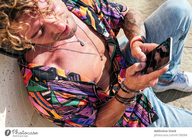 Junger trendiger Mann mit Smartphone im Park Hipster Lächeln soziale Netzwerke jung trendy benutzend Nachricht männlich Mobile Gerät sonnig Telefon Browsen