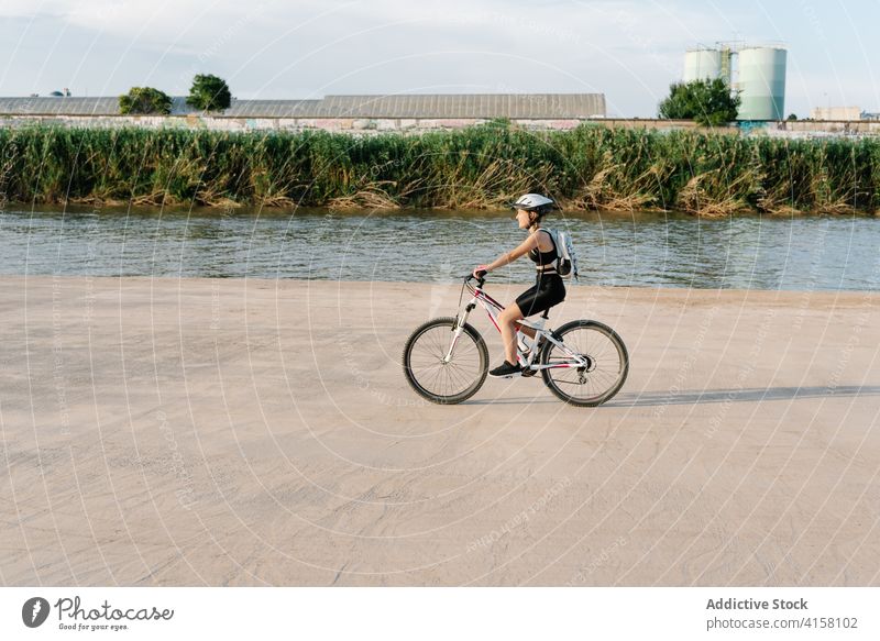 Glückliche Frau fährt Fahrrad auf unbefestigtem Weg Mitfahrgelegenheit Radfahrer Aktivität sportlich Natur Landschaft heiter Übung jung Schutzhelm Lifestyle