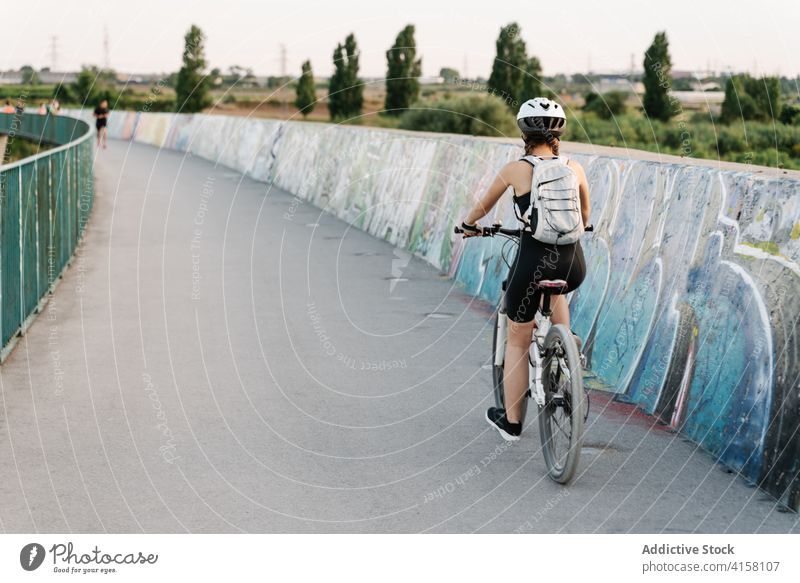 Aktive Frau fährt Fahrrad auf einer asphaltierten Straße Mitfahrgelegenheit Radfahrer Aktivität sportlich Weg Sport Übung jung Schutzhelm Lifestyle genießen
