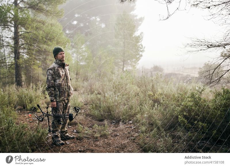Männlicher Jäger mit Bogen im nebligen Wald Mann jagen Schleife Tarnung Verbindung Wälder Bogenschütze männlich Gerät Bogensport modern Pfeil Fähigkeit