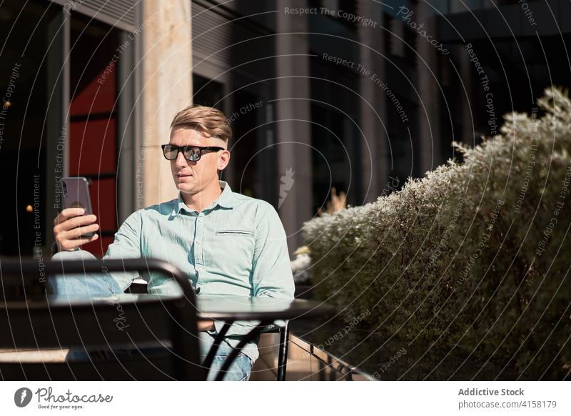 Zufriedener Geschäftsmann beim Surfen auf dem Smartphone in einem Café im Sommer abgelegen Arbeit Unternehmer maskulin gutaussehend benutzend männlich Apparatur