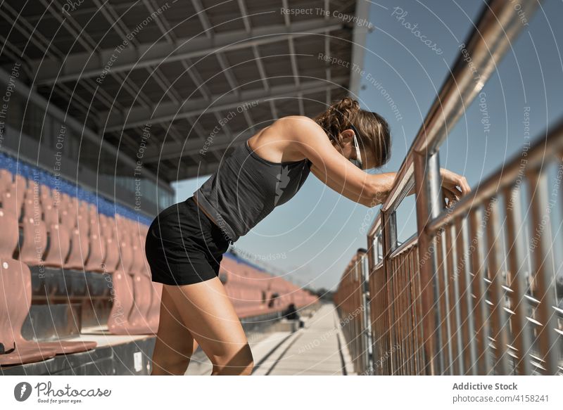 Sportliche Frau ruht sich nach dem Training im Stadion aus Sportlerin müde ruhen passen Fitness Übung Erholung erschöpft sich[Akk] entspannen Pause sportlich