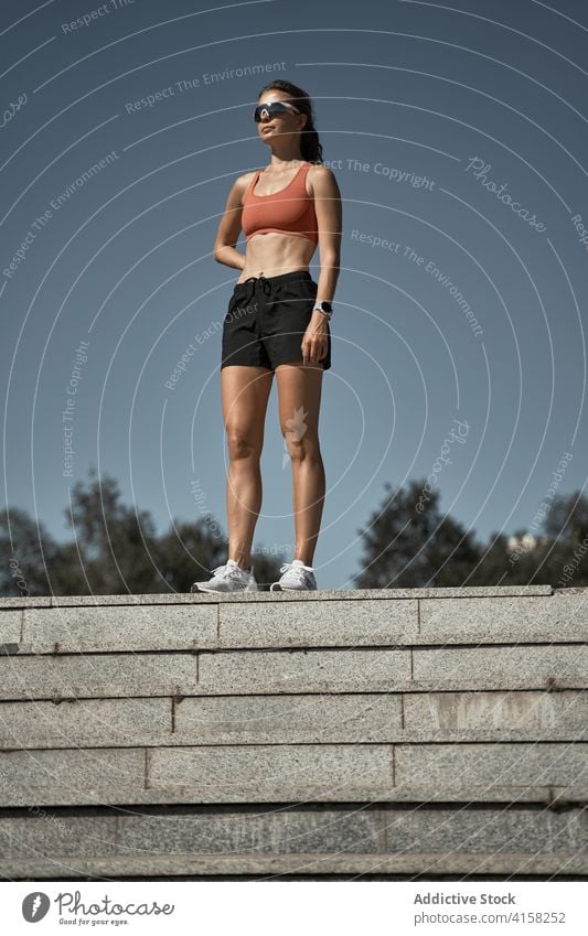 Junge fitte Frau in Sportkleidung steht auf einer Treppe auf der Straße Sportlerin passen schlank Schritt Treppenhaus selbstbewusst Training Fitness Erholung