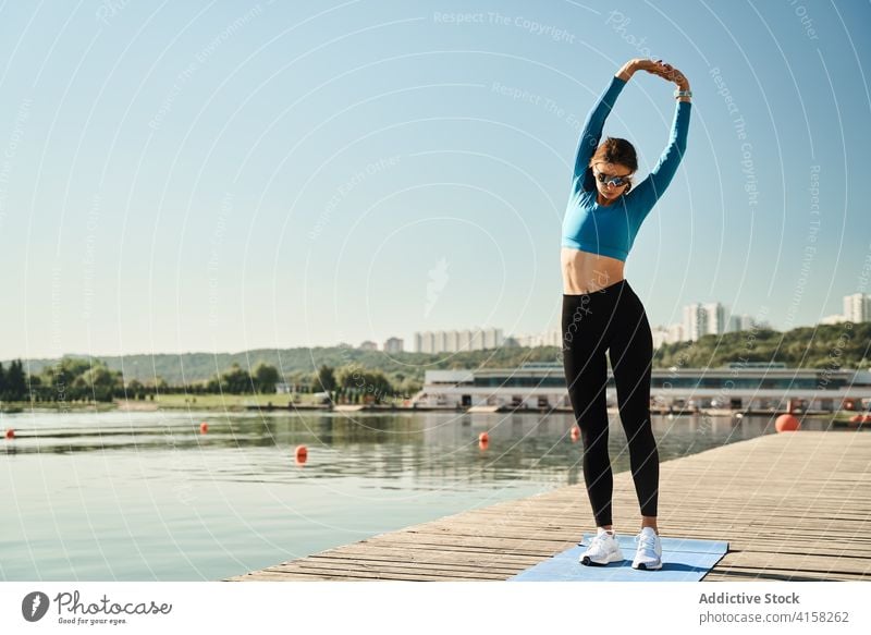 Sportliche Frau streckt ihren Körper am Flussufer Training Dehnung passen schlank Fitness Übung Stauanlage sportlich Wegbiegung aktiv Aufwärmen Gesundheit Ufer