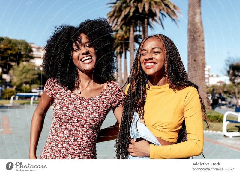 Lächelnd schwarze Frauen zu Fuß entlang Straße zusammen Freund Spaziergang tropisch Zusammensein Händchenhalten Freude Freundschaft bester Freund Sommer