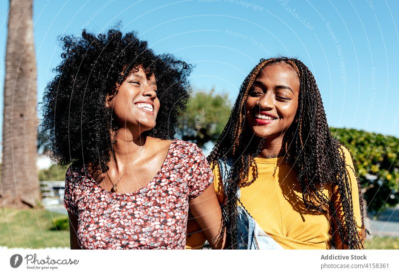Lächelnd schwarze Frauen zu Fuß entlang Straße zusammen Freund Spaziergang tropisch Zusammensein Händchenhalten Freude Freundschaft bester Freund Sommer