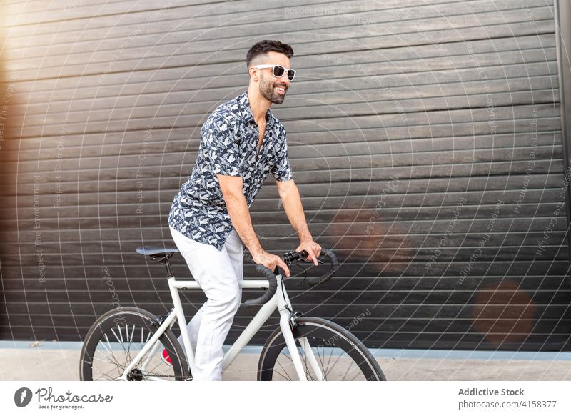 Lächelnder Mann fährt Fahrrad auf der Straße Mitfahrgelegenheit Reiter Radfahrer Stil trendy Großstadt heiter männlich gutaussehend maskulin Hobby modern