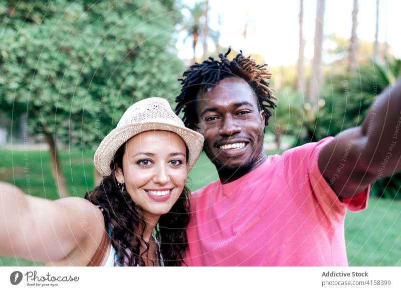 Lächelndes multiethnisches Paar macht Selfie im Park reisen Smartphone Moment genießen Abenteuer Fernweh benutzend rassenübergreifend vielfältig schwarz