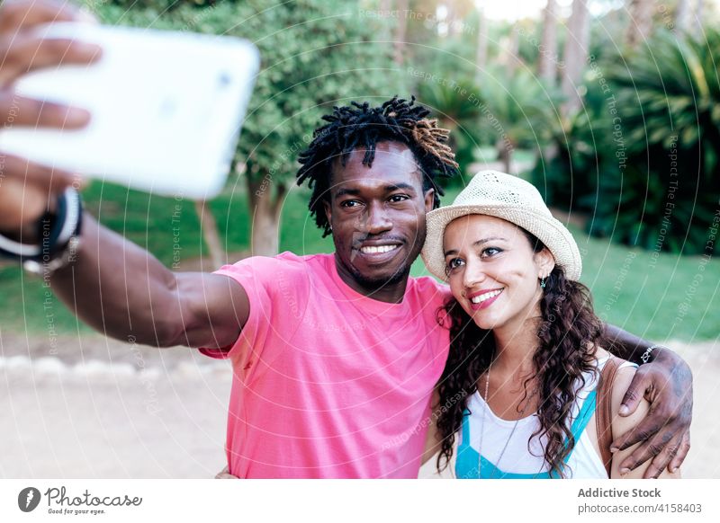 Lächelndes multiethnisches Paar macht Selfie im Park reisen Smartphone Moment genießen Abenteuer Fernweh benutzend rassenübergreifend vielfältig schwarz