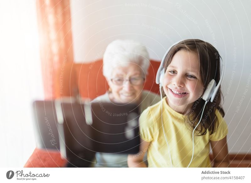 Erfreute Großmutter und Enkelin unterhalten sich per Videochat Video-Chat Videoanruf Generation Smartphone Wellenhand Zusammensein heiter benutzend Gerät