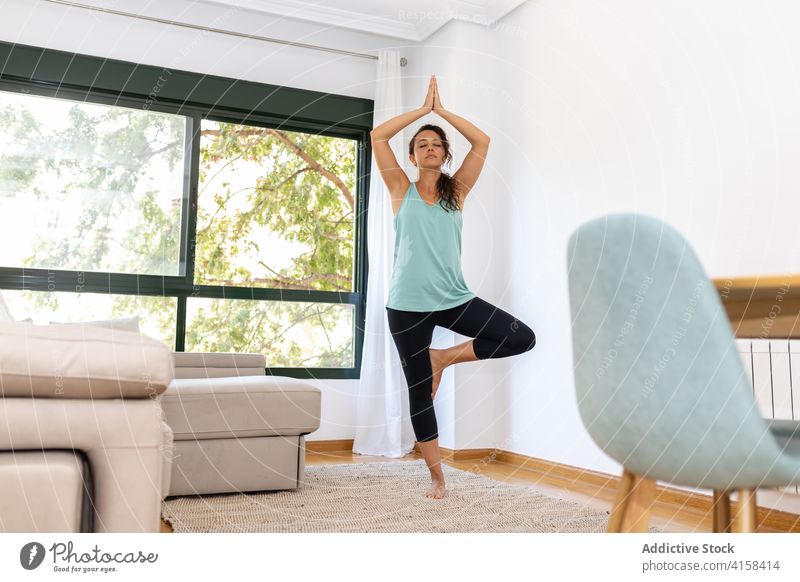 Entspannte Frau macht Yoga in Baumhaltung zu Hause heimwärts meditieren vrksasana Harmonie üben Gleichgewicht Barfuß Vitalität ruhig Gelassenheit schlank