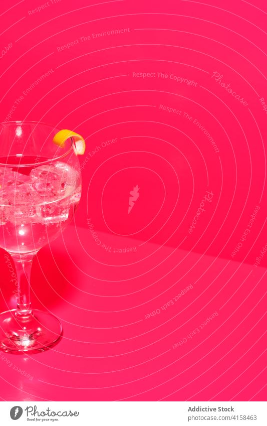 Glas Gin Tonic in der Zusammensetzung mit Zitrone auf dem Tisch in rosa Hintergrund Alkohol Geschmack trinken Zitrusfrüchte Getränk Frucht frisch Flüssigkeit