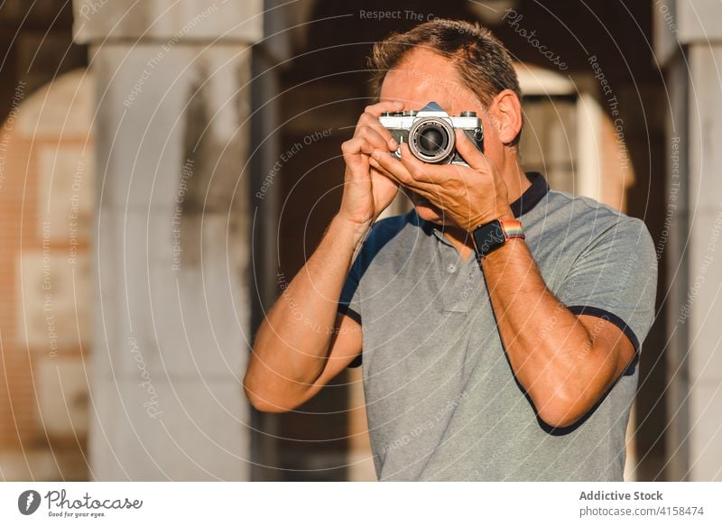 Mann fotografiert mit alter Kamera in der Stadt Fotograf retro Fotokamera Straße Fotoapparat altehrwürdig fotografieren sonnig Sommer männlich Hobby Großstadt