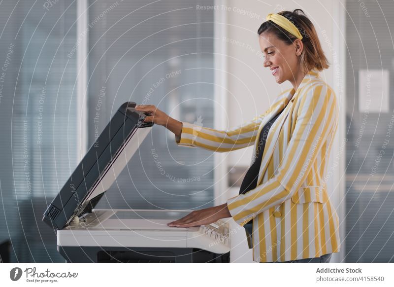 Positiv eingestellte schwangere Geschäftsfrau bei der Benutzung eines Fotokopierers Frau Arbeit Scanner Maschine xerox Kopie Schriftstück benutzend Papier