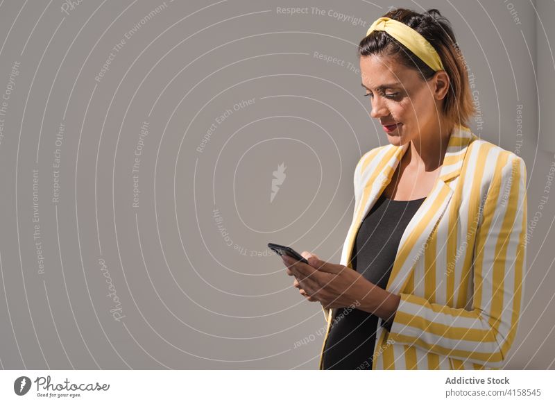 Moderne schwangere Frau in modischem Outfit mit Smartphone benutzend Stil Telefon Nachricht Browsen Apparatur modern trendy positiv gelb Streifen Mobile Gerät