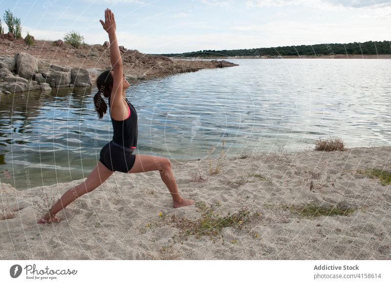 Junge Frau macht ausgleichende Yoga-Asana in der Nähe eines Sees üben Krieger virabhadrasana Pose Gleichgewicht stehen Harmonie Wellness Lifestyle Konzentration