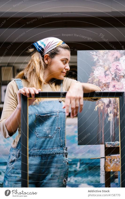 Weiblicher Handwerker mit Rahmen in einer Kunstwerkstatt stehend Frau Künstler Farbe Staffelei kreativ Werkstatt Arbeit Bild Talent Leinwand Hobby Inspiration
