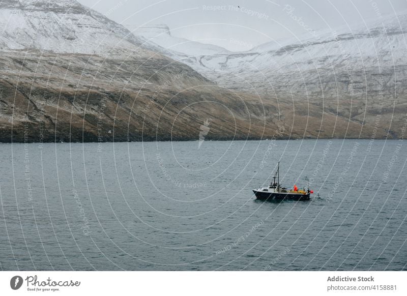 Fischkutter auf dem Meer in der Nähe des schneebedeckten Berges verschneite Fischerboot Tourismus Landschaft Fähre Himmel Natur Wasser blau reisen kalt Schnee