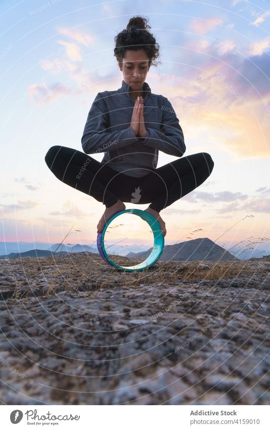 Junge Frau balanciert auf einem Yoga-Rad in der Natur Gleichgewicht malasaña Girlande Asana Gerät Pose Berge u. Gebirge Felsen üben positionieren Wellness