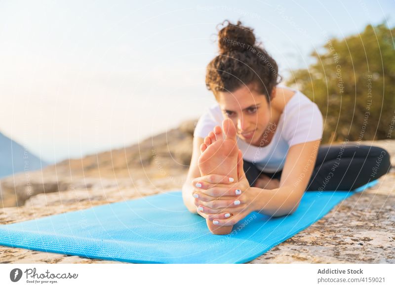 Flexible Frau beim Dehnen in einer Yoga-Asana in der Natur Von Kopf bis Knie sitzen weitergeben Wegbiegung Dehnung Janu Sirsasana beweglich Pose