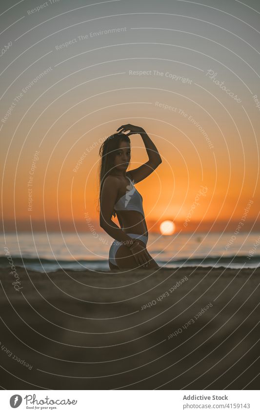 Frau im Badeanzug am Strand bei Sonnenuntergang sich[Akk] entspannen schlank Ufer Seeküste Sommer Urlaub MEER Himmel Wasser Sand Feiertag Natur Freiheit
